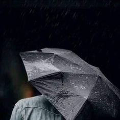 a person holding an umbrella in the rain with it's light shining on them