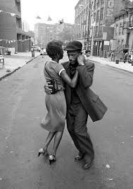 a man and woman dancing on the street in an old black and white photo,