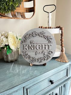 a wooden sign that says knight lady on top of a blue dresser next to flowers