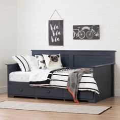 a dog laying on top of a bed in a bedroom next to a rug and pictures