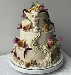 a three tiered cake with figurines and flowers on it