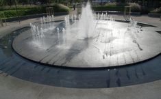 a water fountain in the middle of a circular area with several fountains on each side