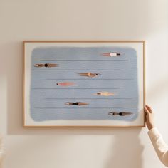 a person is holding up a painting on the wall with different types of fish in it