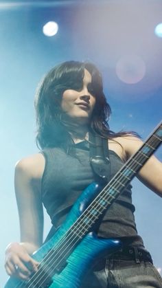 a woman holding a blue guitar in her right hand