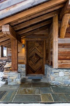 the front door of a log cabin with stone and wood trimmings on it