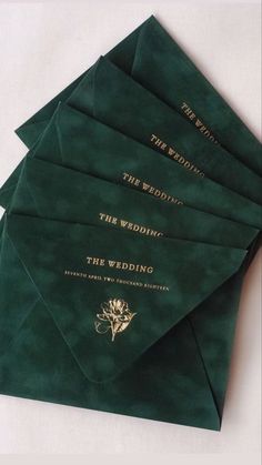 five green envelopes with gold lettering on them