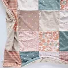 an old patchwork blanket is laying on top of a white surface with flowers and stars