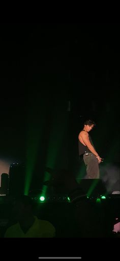 a man standing on top of a stage in front of green lights