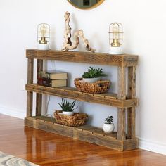 a wooden shelf with baskets and plants on it in front of a wall mounted mirror