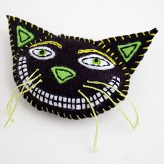 an embroidered black cat with green eyes and whiskers on it's head