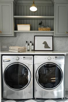 a washer and dryer in a small room with gray cabinets on the wall