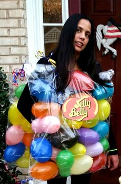 a woman standing in front of a door holding a bag full of balloons with the words hello kitty on it