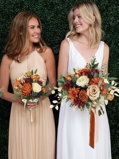 two beautiful women standing next to each other holding bouquets