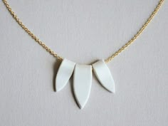 a necklace with three white leaves hanging from it