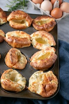 a muffin tin filled with different types of baked goods next to eggs and herbs