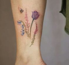 a woman's foot with purple flowers and a bee on the left side of her leg