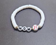 Baseball Mom Clay Bead Bracelet | Personalizable Heishi Baseball Mom Stretch Bracelet | Stackable Bracelets Gift for Her IMPORTANT NOTE: This listing is for a single bracelet or up to 2 bracelets depending on option selection. Details: Handmade Item Bracelet Length: See Size Chart in Images Materials: 4mm silver or gold plated beads (tarnish resistant), plastic letter beads, baseball charm bead Closure: Tie Made to Order Personalization: Bead Colors: See color chart in images Accent Bead Colors: White Round Charm Bracelet With Letter Beads, White Letter Beads Charm Bracelet, Adjustable Stackable White Charm Bracelet, Personalized White Wristband Bracelet, Adjustable Hypoallergenic White Charm Bracelet, Personalized White Beaded Bangle Bracelet, Adjustable White Charm Bracelet With 8mm Beads, Adjustable White Charm Bracelet With Beads, White Bracelets With Letter Beads