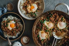 two bowls filled with rice and eggs on top of a table next to utensils