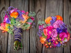 two bouquets of colorful flowers sitting on top of a wooden table next to each other