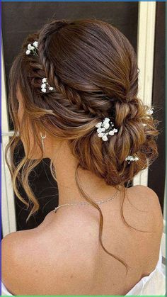 the back of a woman's head with white flowers in her hair and braid