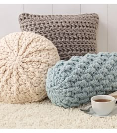 three crocheted pillows and a coffee cup on the floor