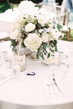 the table is set with white flowers and silverware