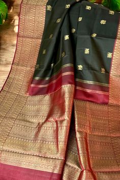 This banarasi inspired stunning kanjivaram saree in kanchana black is handwoven with traditional motifs in gold zari on the body. The borders in deep maroon have traditional motifs like floral, chakras and geometric patterns in gold zari. The grand pallu in deep maroon color mirrors the patterns of the borders in gold zari. Approximate Length 6.5 mtrs (inclusive of blouse length) Approximate weight - 1.5 lbs Approximate Height - 48 - 52" Saree comes with fall, picot and tassels done when applicable. Blouse piece is cut. Kindly Note : The colors you see on your device may vary due to the color reproduction, brightness and resolution of individual devices. If you'd like more clarity before your purchase, please contact our support team. Black Raw Silk Saree With Cutdana, Black Raw Silk Saree With Pallu, Black Tussar Silk Dupatta For Navratri, Black Paithani Silk Handloom Dupatta, Black Handloom Paithani Silk Dupatta, Black Handloom Anarkali Dupatta, Black Paithani Silk Saree With Traditional Drape, Anarkali Style Black Handloom Dupatta, Traditional Black Raw Silk Dupatta