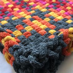 a multicolored crocheted blanket laying on top of a white tablecloth