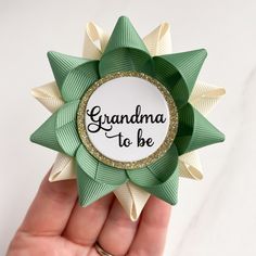 a hand holding a green and white flower with the words grandma to be on it