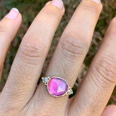 a woman's hand with a ring on it and a pink stone in the middle