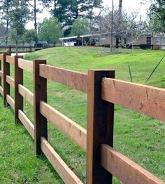 a wooden fence in the middle of a grassy field