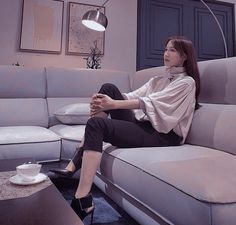 a woman sitting on top of a couch in a living room next to a coffee table