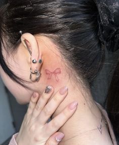 a woman with a tattoo on her neck and behind her ear is looking at the camera