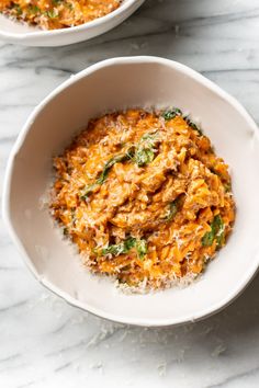 two white bowls filled with food on top of a table