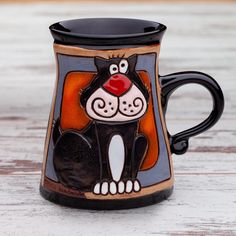 a black and white cat mug sitting on top of a wooden table with a red nose