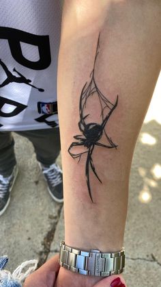 a woman's arm with a black spider tattoo on the left side of her arm