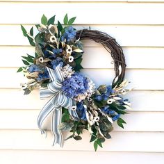 a wreath with blue and white flowers hanging on the side of a house