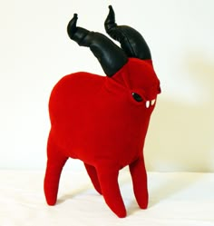 a red stuffed animal with black horns on it's head