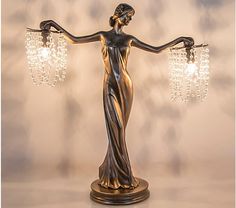 a bronze statue holding two crystal chandeliers in it's arms and hands