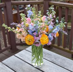 a vase filled with colorful flowers on top of a wooden table