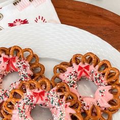 three pretzels with pink frosting and sprinkles on a plate