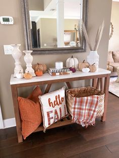 a wooden table topped with lots of pillows and pumpkins next to a large mirror