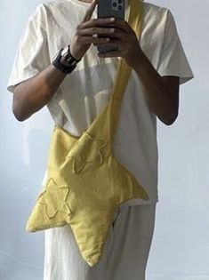 a man holding a cell phone in his right hand while wearing a yellow star shaped bag