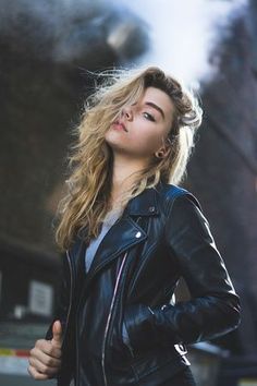 a woman in a black leather jacket posing for the camera