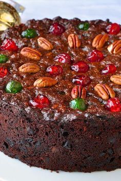 a chocolate cake with pecans, cherries and nuts on top is sitting on a white plate