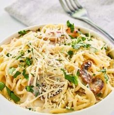 a white bowl filled with pasta covered in parmesan cheese and garnished with fresh herbs