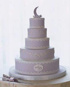 a three tiered wedding cake with the moon on top and two forks beside it