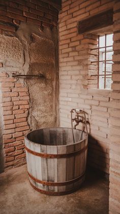 an old wooden barrel sitting in the corner of a room next to a brick wall