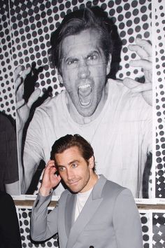 a man in a gray suit and white shirt posing for the camera with his mouth open