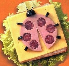 a ladybug sandwich with cheese and lettuce on it's side